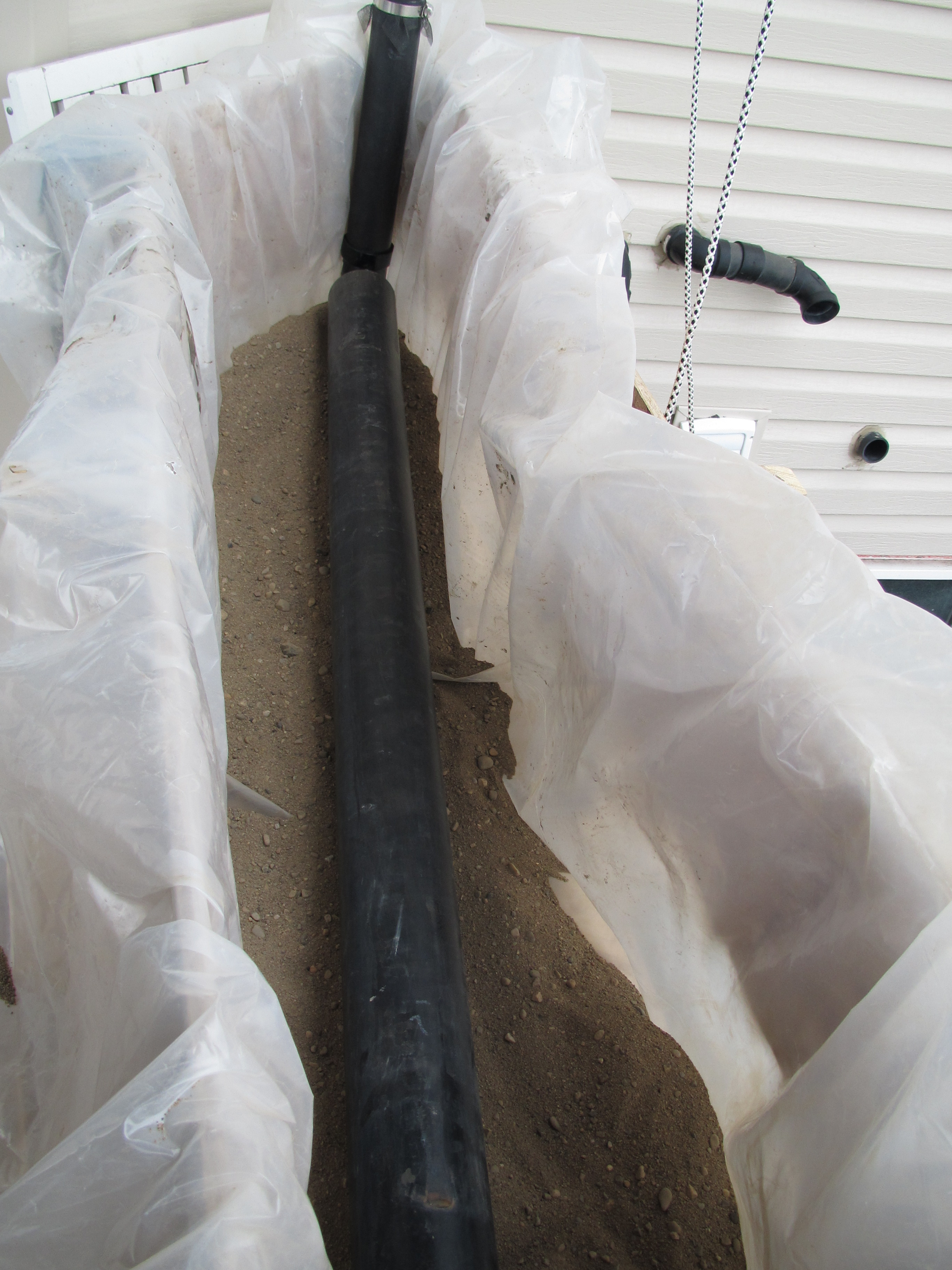 Showing the 3" drainage pipe on the bottom and the plastic liner. some gravel on the bottom to rest the pipe on.