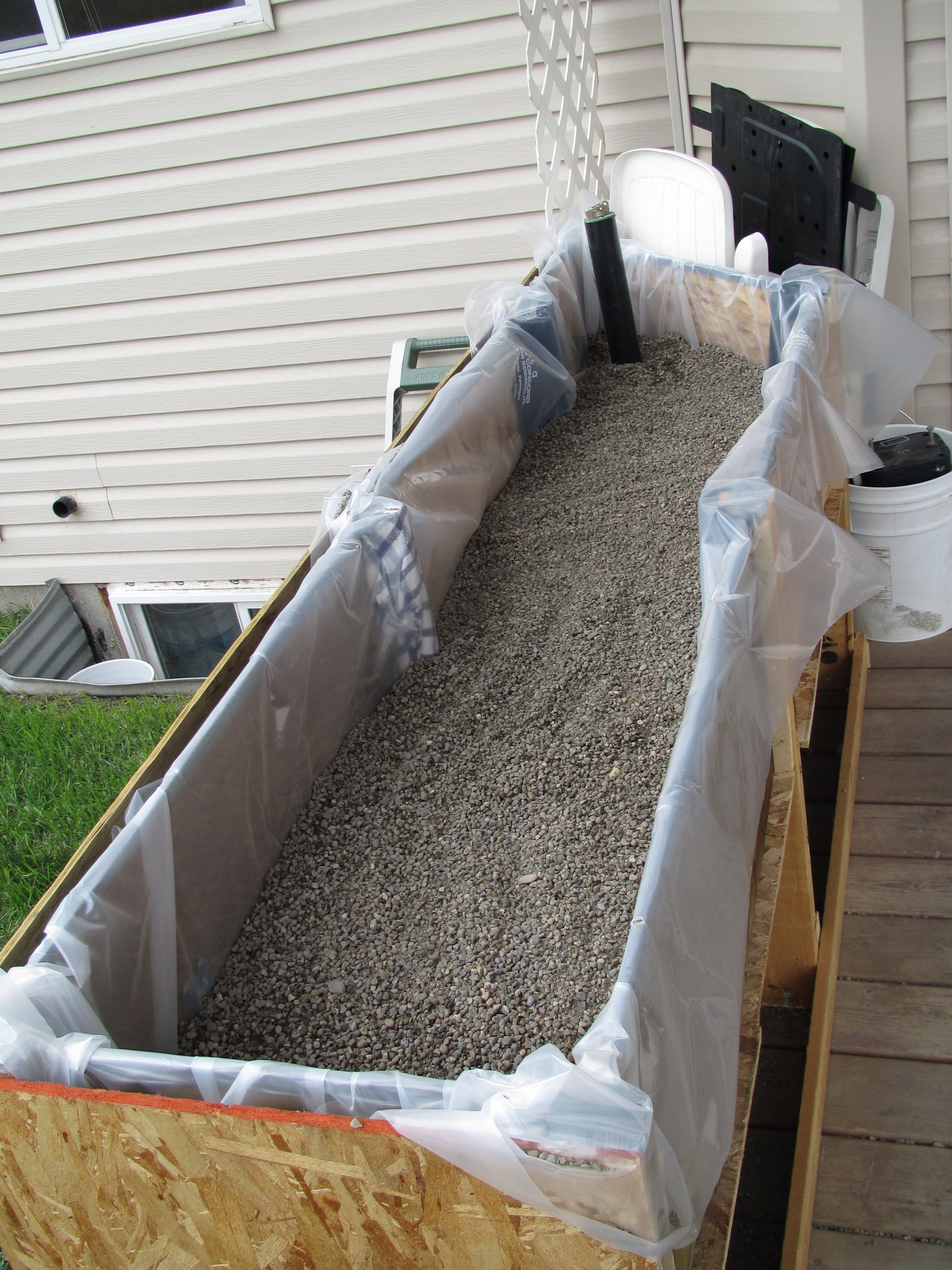 Gravel in to the top of the pipe. From here, I put landscape fabric in one of the beds, but not the other one. I just replaced these two and can say it made no real difference in the vegetable garden. It might be different if the bed was being used for perennials.